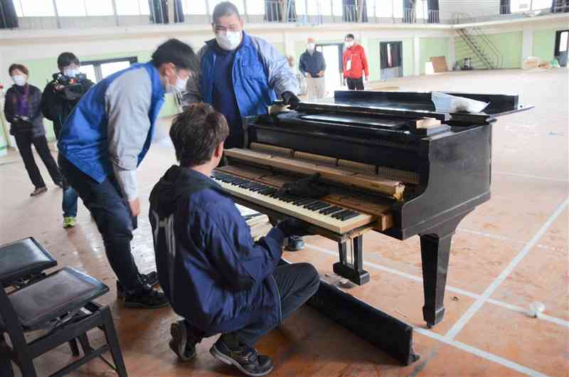 旧藤本小のグランドピアノを運搬するために作業する業者＝3月、八代市