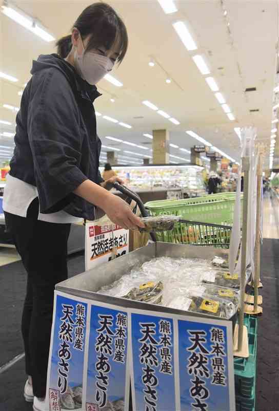 福岡県内の一部店舗で販売が再開した、熊本県産アサリを手に取る消費者＝28日、福岡県大牟田市