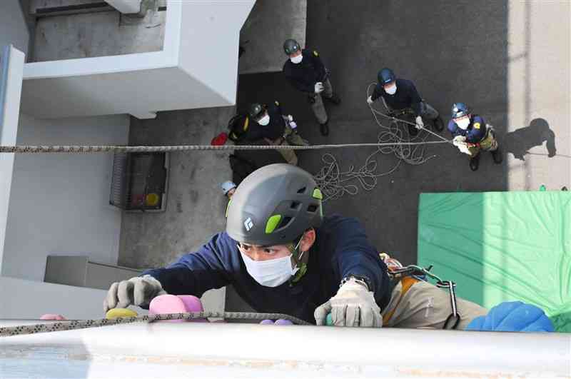阿蘇署の壁面でクライミングに挑む県警山岳救助隊員＝阿蘇市