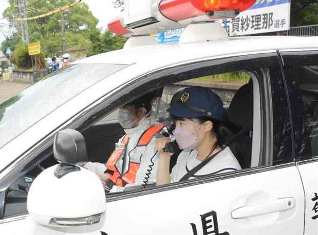 登校中の生徒らにパトカーから交通安全を呼びかける中学生DJポリス＝大津町