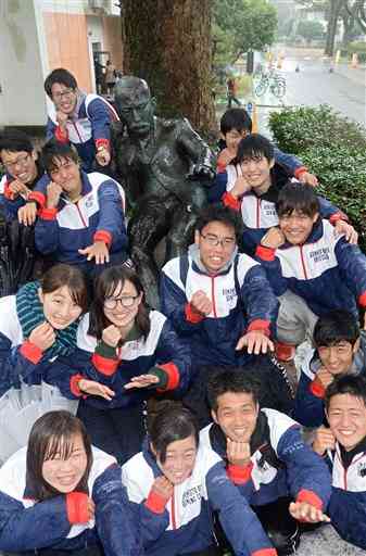 夏目漱石の銅像の前でポーズをとる熊本大ボート部の学生たち＝熊本市の熊本大黒髪キャンパス（2016年3月撮影、横井誠）