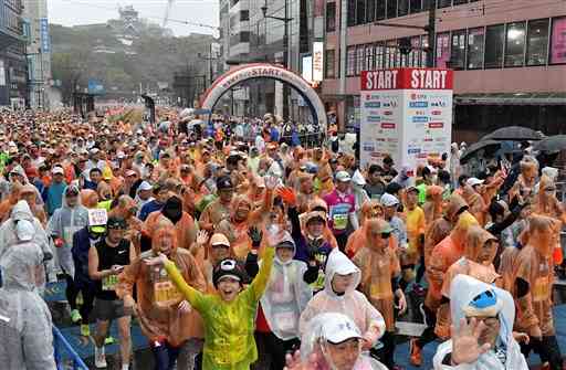 雨の中、通町筋をスタートする第9回熊本城マラソンのランナー＝2020年2月、熊本市中央区