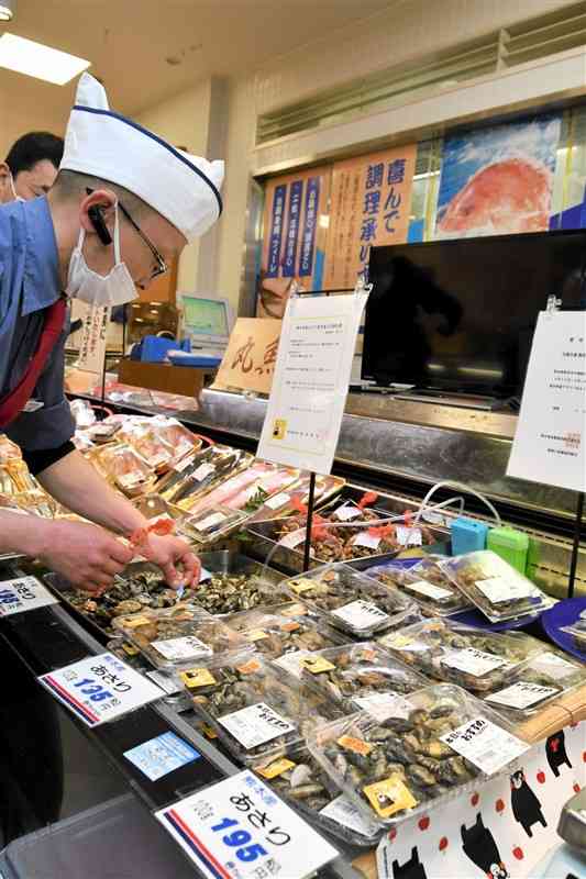 県内販売の再開初日、鶴屋百貨店の鮮魚売り場に県産アサリを並べる担当者。6月中旬から全国出荷が再開予定＝4月14日、熊本市中央区