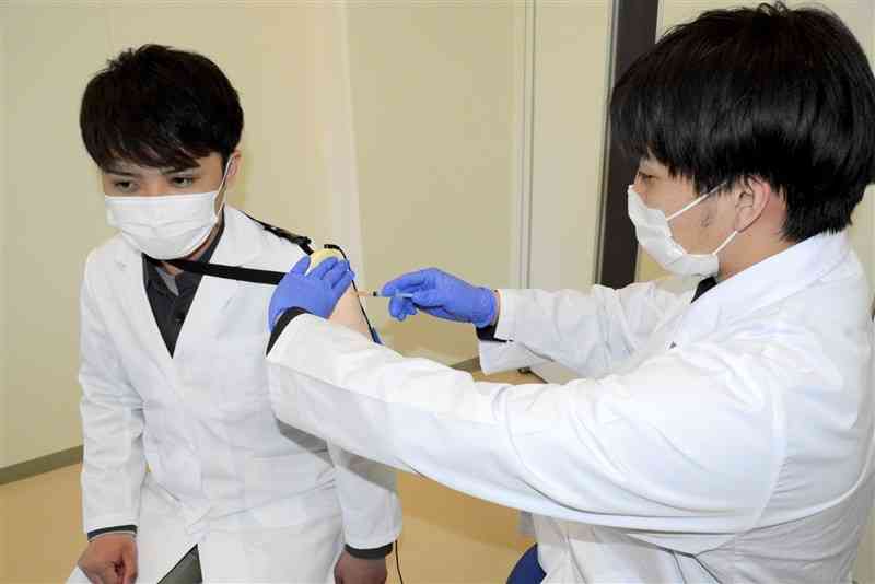 シミュレーターを使ってワクチン接種の練習をする崇城大の薬学部生＝4月4日、熊本市西区
