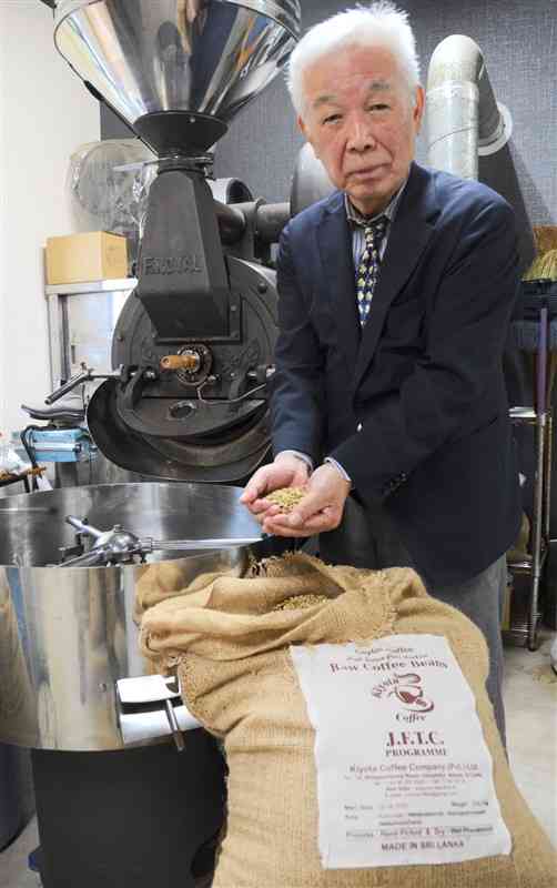 スリランカ産のコーヒー豆を手にする清田和之さん。経済危機に陥った同国を支援しようと、現地の特産品の直売所を開く＝熊本市北区