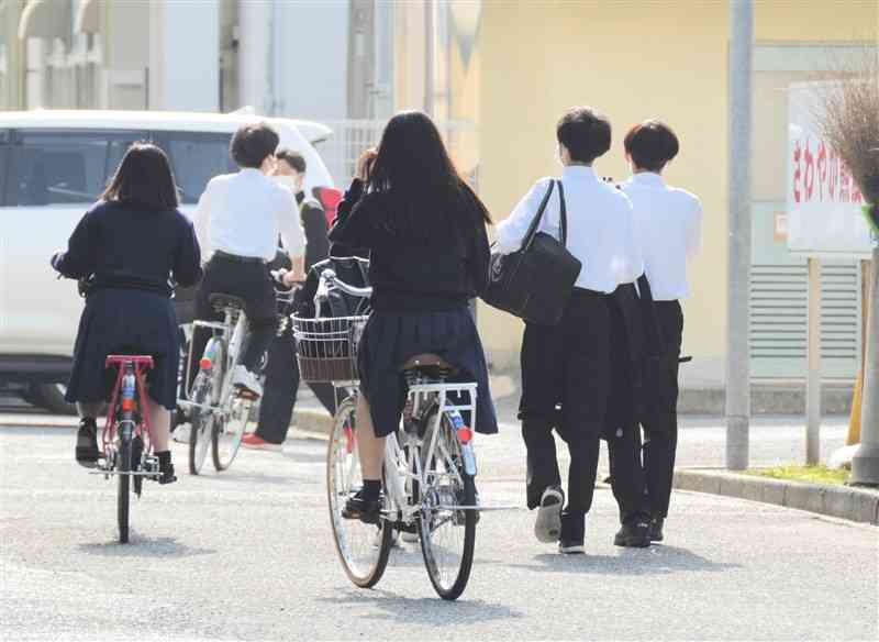 登校する熊本農高の生徒たち。昨年まで禁止されていたツーブロックの髪形や、肩に触れる髪の長さでも束ねずに下ろしている生徒が見受けられた＝4月28日、熊本市中央区