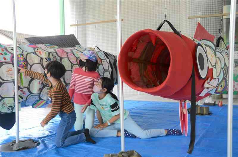 描いた絵をジャンボこいのぼりに張り付ける子どもたち＝熊本市中央区