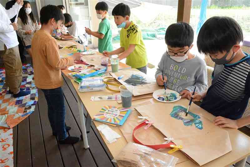 「米バッグ」に絵を描く児童たち＝大津町