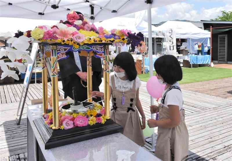 花御堂で釈迦像に甘茶をかける子どもたち＝湯前町