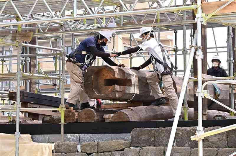 監物櫓の建物部分の復旧工事が始まり、梁をクレーンで持ち上げる準備をする作業員＝10日午前、熊本市中央区（石本智）