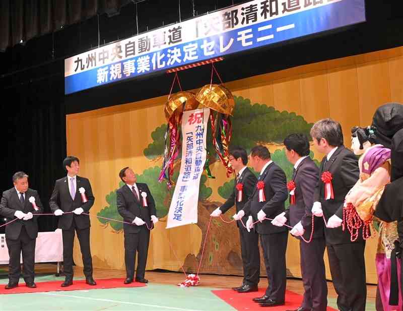 くす玉を割って、九州中央自動車道矢部清和道路の事業化を祝う沿線自治体の首長ら＝山都町