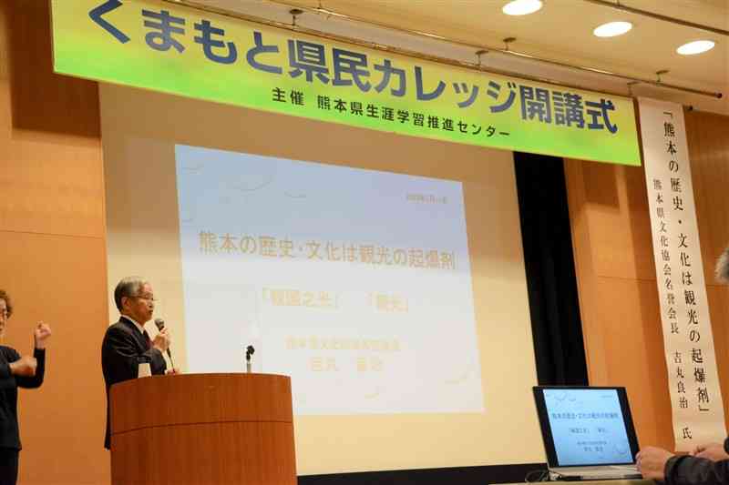 くまもと県民カレッジの開講式で講演する県文化協会の吉丸良治名誉会長（左）＝熊本市中央区