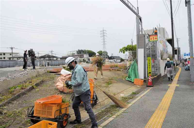 旧熊本市民病院の解体工事が再開し、敷地内の除草作業をする工事関係者＝熊本市東区