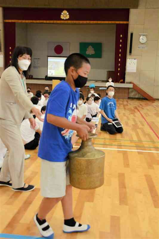 15キロの水がめを持ち運んで世界の子どもの課題について学ぶ児童＝熊本市中央区