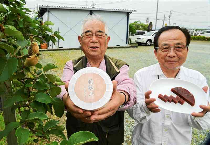 復刻させた「かせいた」を持つ走潟マルメロ会の芥川雄二会長（左）らのメンバー。左は走潟公民館に植えられたマルメロ会の木＝宇土市