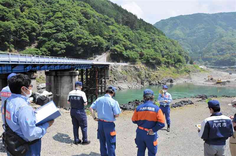 梅雨期を前に球磨川を巡視する国や八代市の職員ら。後方に見えるのは豪雨で流出した鎌瀬橋の仮橋＝八代市