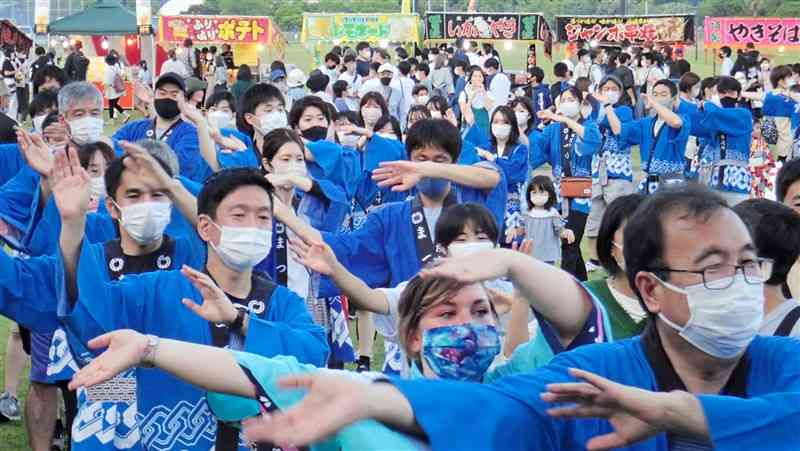 大きく手を振って踊る市民総踊りの参加者ら＝水俣市