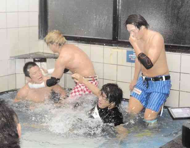 大浴場の浴槽で技を掛け合うプロレス選手ら＝熊本市西区