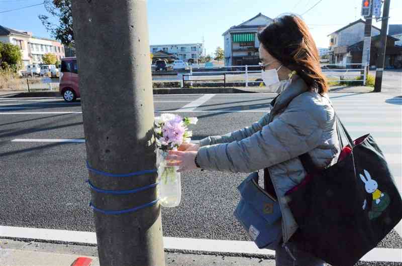 次男をはねた男性が不起訴となった後、事故現場に花を手向ける平井沙紀さん＝3月6日、天草市