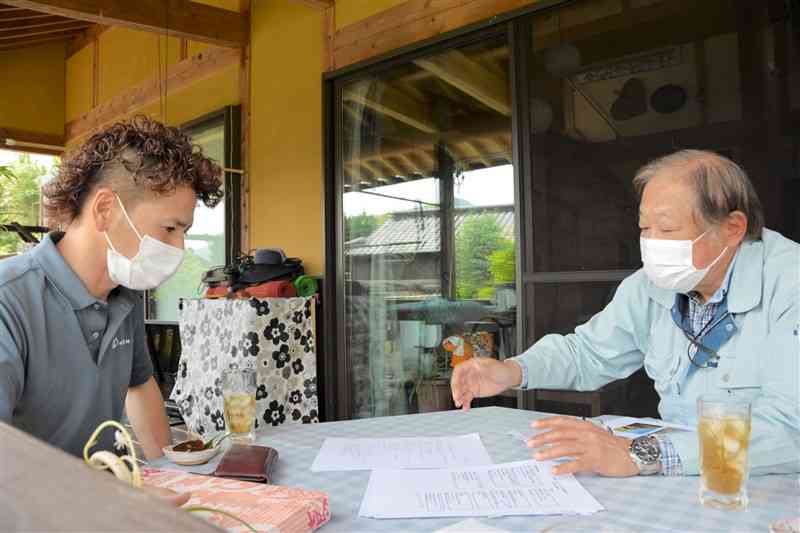 和水町瀬川地区でエリアンサスを栽培する委託契約について説明を受ける土地所有者の杉本慎也さん（左）＝同町