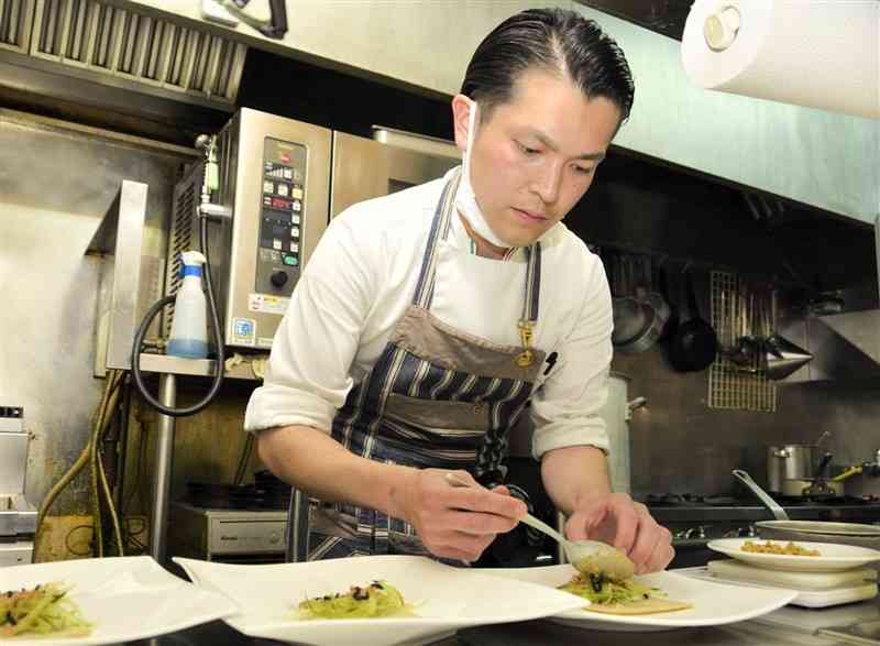そば粉クレープの前菜を皿に盛り付けるシェフの上田悟さん＝熊本市東区