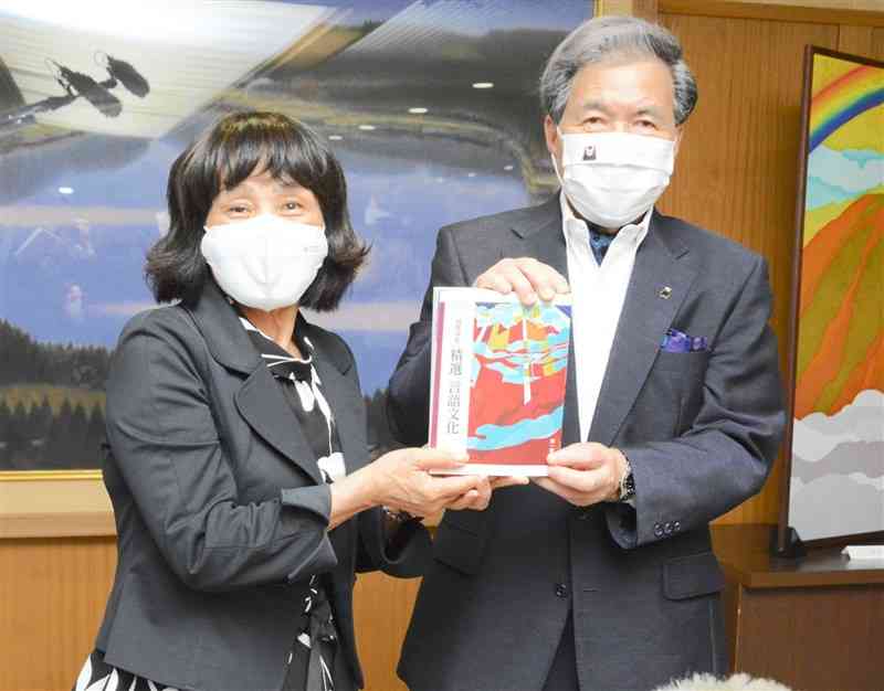 蒲島郁夫知事（右）に教科書を手渡した染色家の高津明美さん＝県庁