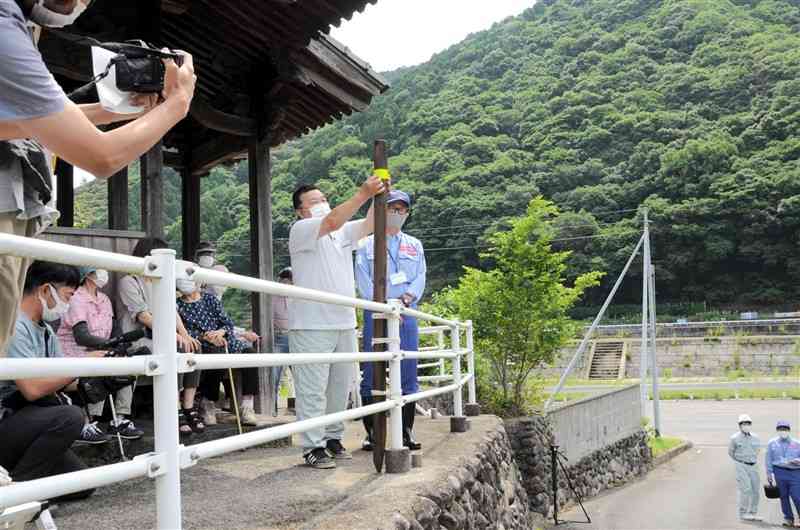 かさ上げ後の宅地の高さにテープを貼り付ける松村義美自治会長ら＝八代市