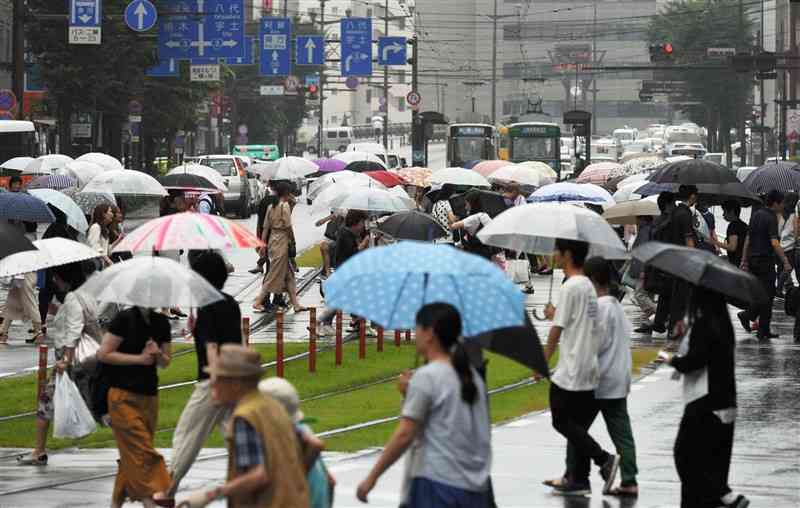 降り続く雨の中、傘を差して足早に行き交う人々（上杉勇太）