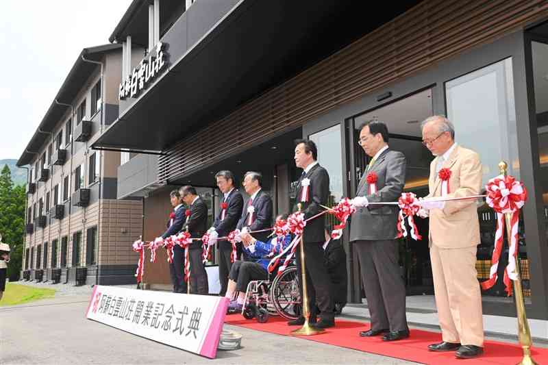 テープカットして阿蘇白雲山荘の新築再建を祝う関係者ら＝阿蘇市