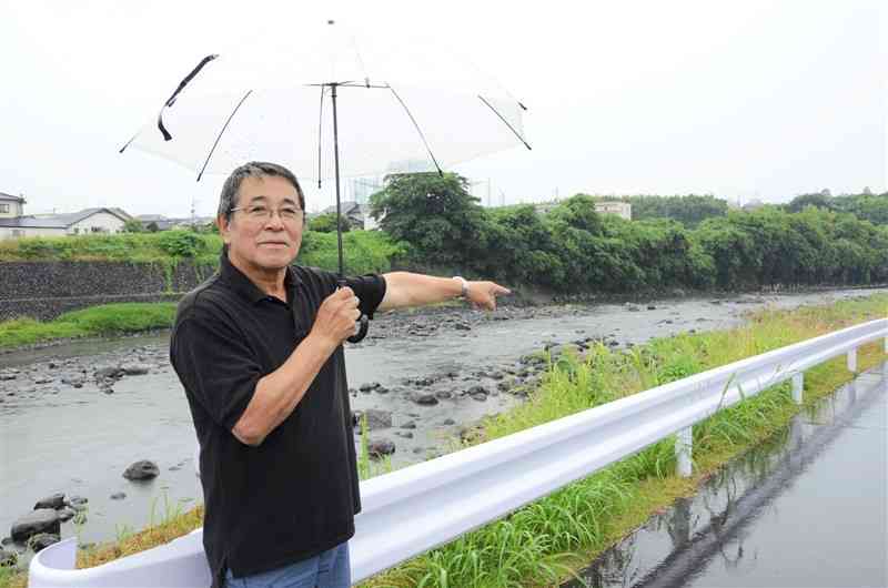 九州北部豪雨で氾濫した白川の前で、当時の様子を振り返る高田敏明さん。濁流が押し寄せ、住民は逃げ場を失ったという＝13日、熊本市北区龍田1丁目