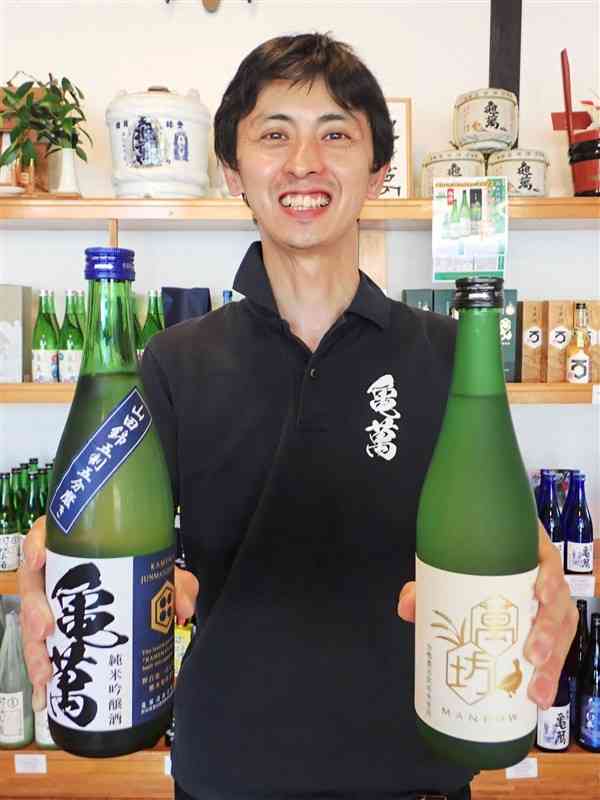 国内外で受賞した酒を持つ亀萬酒造の竹田瑠典専務。「地元の農家にも喜んでもらえる」と話す＝津奈木町