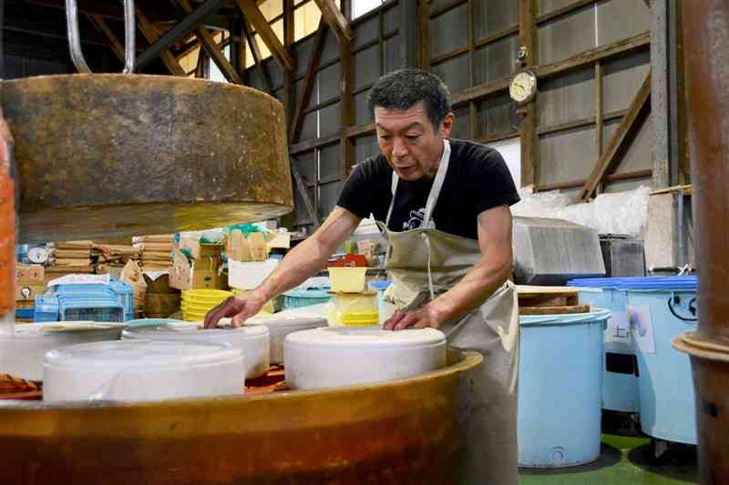 豪雨で亡くなった父誠さんが建てた工場で、漬物作りの作業に打ち込む永尾禎規さん＝18日、相良村