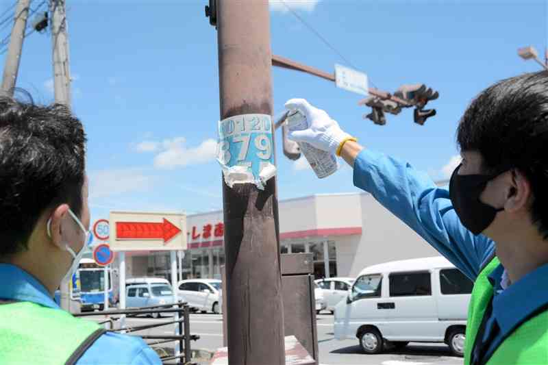 違反広告物に薬剤をスプレーして剝ぎ取る市職員ら＝熊本市西区