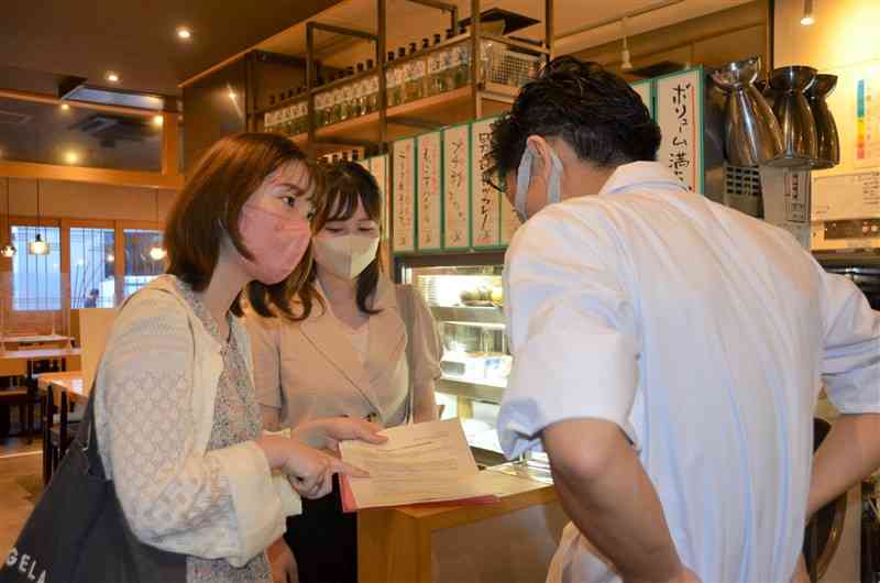 熊本市中央区の餃子屋「さんじ」で「センキョ割」への協力を呼びかける「ドットジェイピー熊本エリア」のメンバー＝6月6日