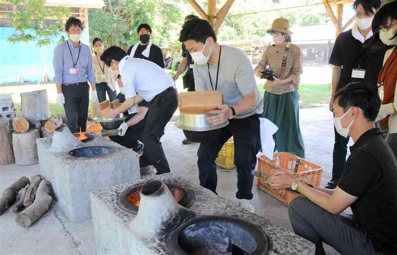 かまどでご飯を炊くツアー参加者＝菊池市