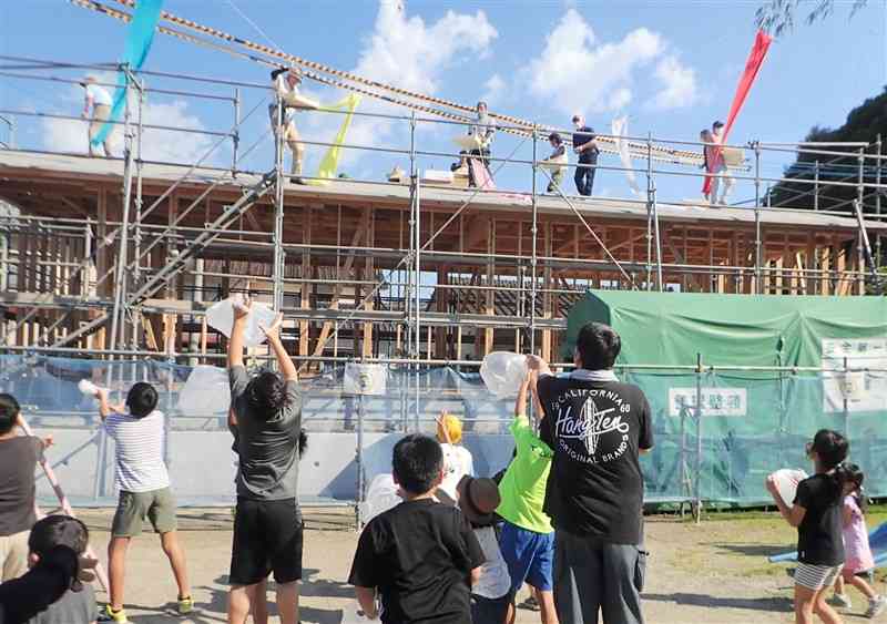 湯浦北区公民館の棟上げ式で、もち投げで盛り上がる住民ら＝芦北町