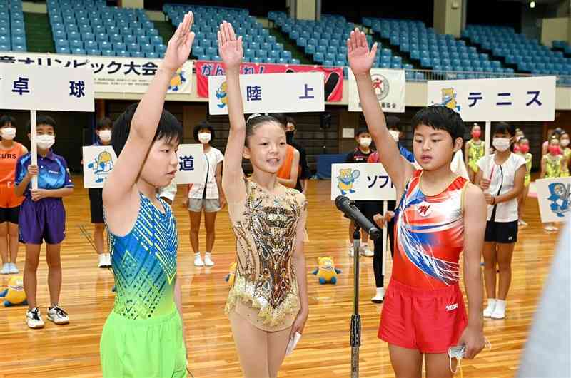 熊日学童オリンピックの総合開会式で選手宣誓する（左から）早川天恵（八代トランポリンクラブ）、岡村雫句（みどり新体操クラブ）、知識颯翔（W体操クラブ）＝2日午前、熊本市西区の県立総合体育館（石本智）