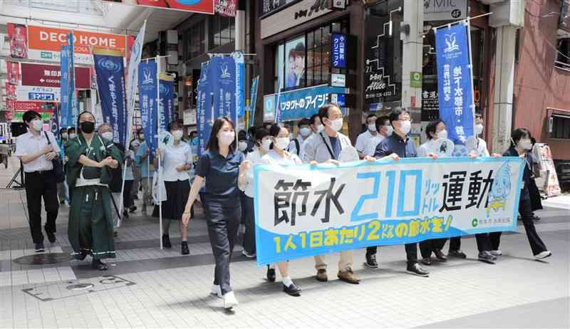 節水を呼びかける横断幕を掲げてアピールする参加者＝熊本市中央区