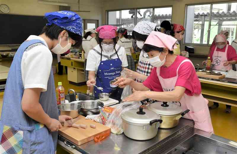 食生活改善指導員（右）に教わりながら、災害時に役立つ料理を作る有明高の生徒ら＝荒尾市