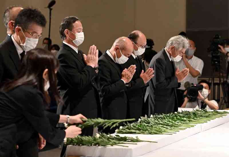 人吉市の豪雨犠牲者追悼式で、祭壇に献花し手を合わせる参列者＝3日午前10時半ごろ、人吉市カルチャーパレス（石本智）