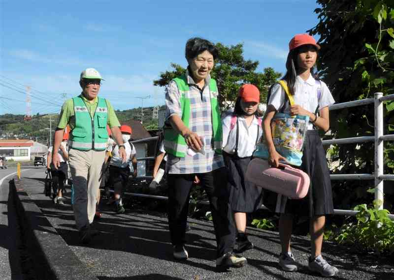 青海小の児童の登校に付き添う前田信幸さん（左）と鈴木菊美さん＝宇城市