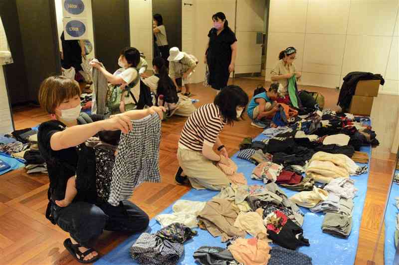 リユースする子ども服を選ぶ母親ら＝熊本市中央区