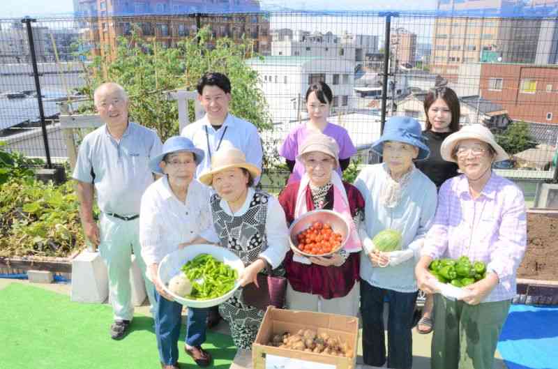 屋上での野菜作りが生きがいになっている「ゆほびか水前寺」の入居者ら＝熊本市中央区