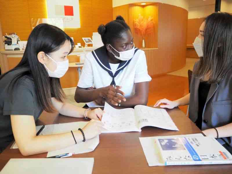 慶誠高の留学生、ジョバ・ローさん（中央）に日本語を教える熊本学園大の竹原このみさん（左）と鈴木友麻さん＝熊本市中央区