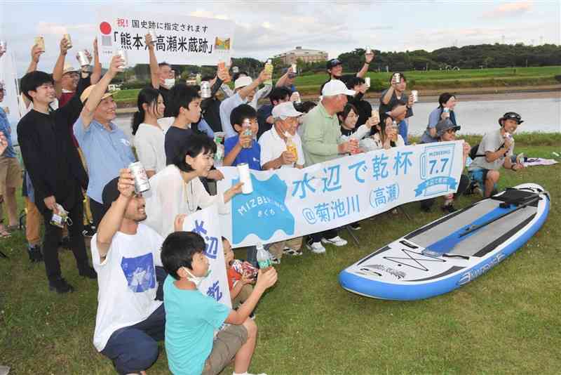 菊池川沿いの高瀬船着場跡で乾杯する「水辺で乾杯」の参加者＝玉名市