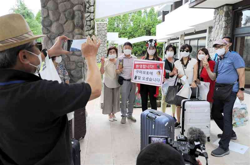 約2年ぶりに受け入れが再開された訪日外国人客の第1陣として来熊し、記念写真に納まる韓国人観光客＝8日午後、高森町