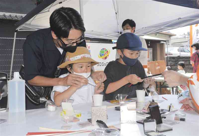 アイシャドーなどの化粧品を再利用してスライムに色付けする来場者＝熊本市中央区