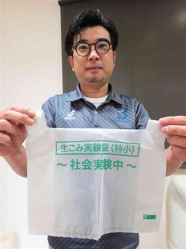 社会実験に使った生分解性プラスチックの袋を持つバイオマスレジン熊本の森功介社長＝水俣市