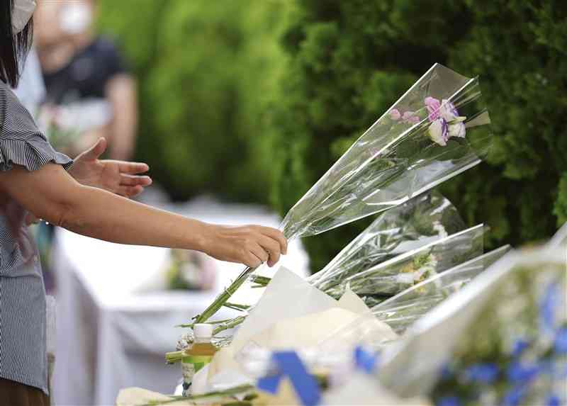 安倍元首相が銃撃された現場近くの献花台に手向けられる花＝12日午後、奈良市