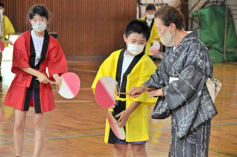 玉名音頭の練習に励む八嘉小の児童と指導する林田優子・玉名市文化協会副会長（右）＝同市